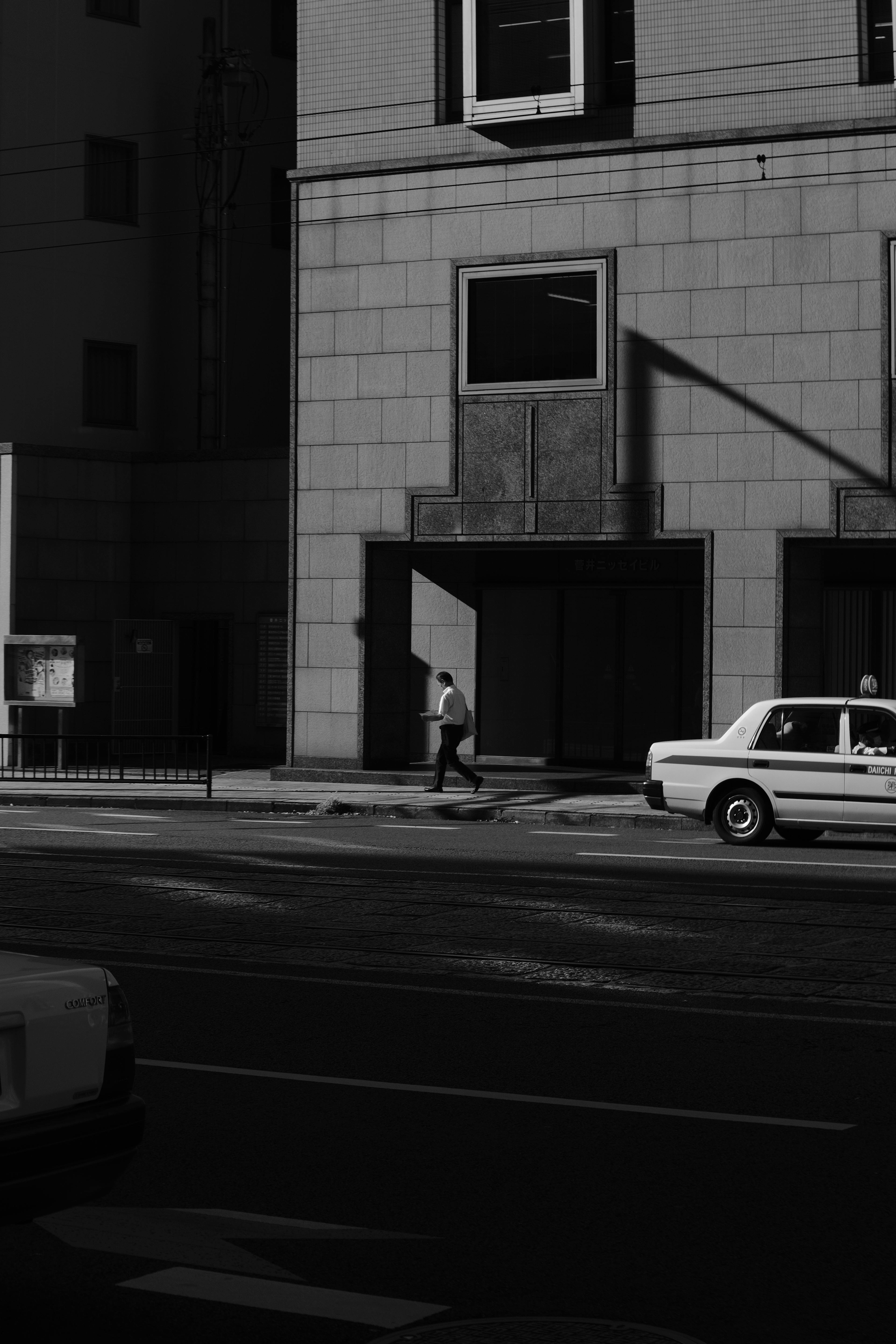 Zadarmo Monochromatický obraz osamelého chodca kráčajúceho okolo budovy v mestskom prostredí. Fotka z fotobanky