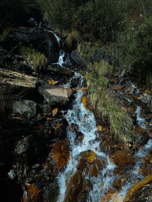 Free A serene mountain stream cascading over rocks amid lush greenery, creating a picturesque natural scene. Stock Photo