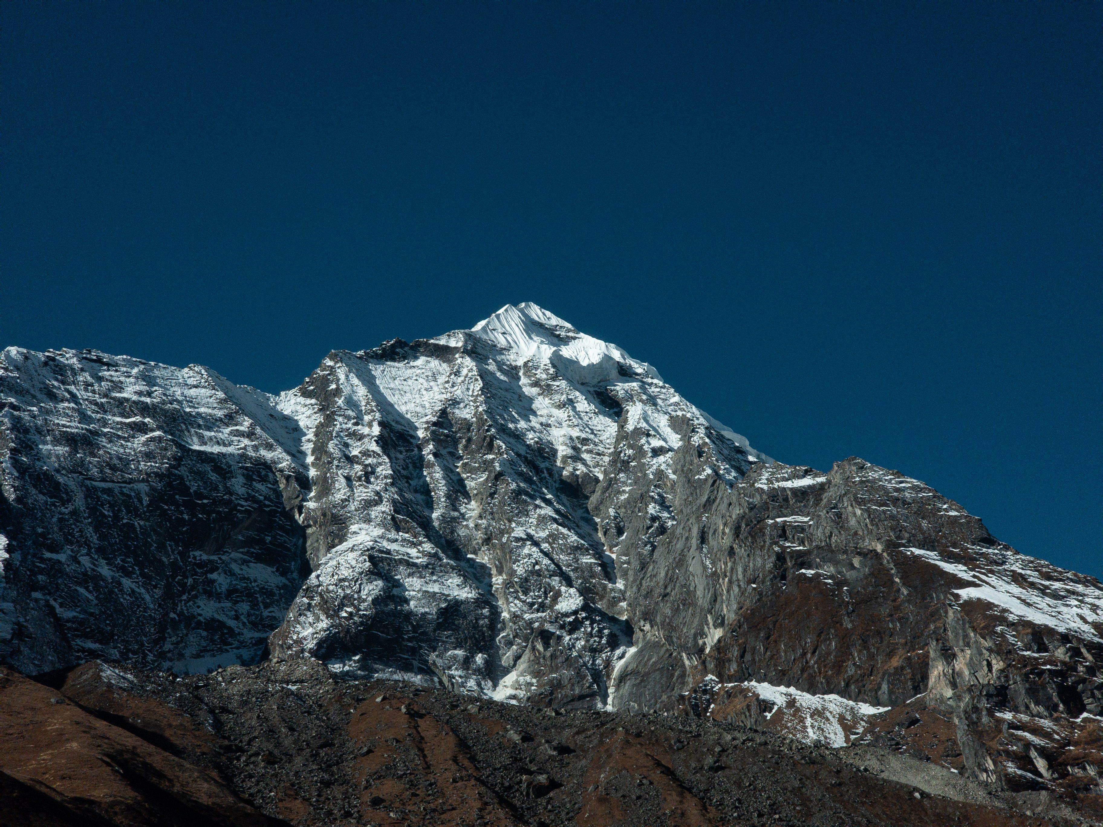 Majestic snow-covered Himalayan peak against a deep blue sky in daylight.