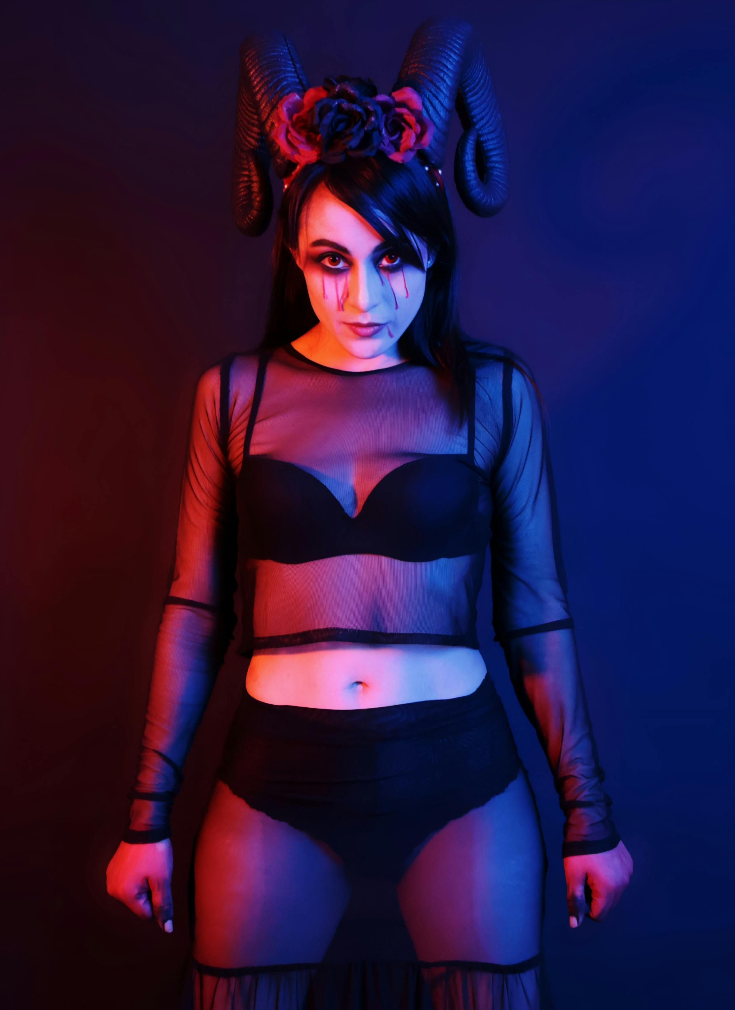 Gratuit Portrait à thème gothique avec un éclairage rouge et bleu dramatique, représentant une femme dans une tenue noire avec des cornes. Photos