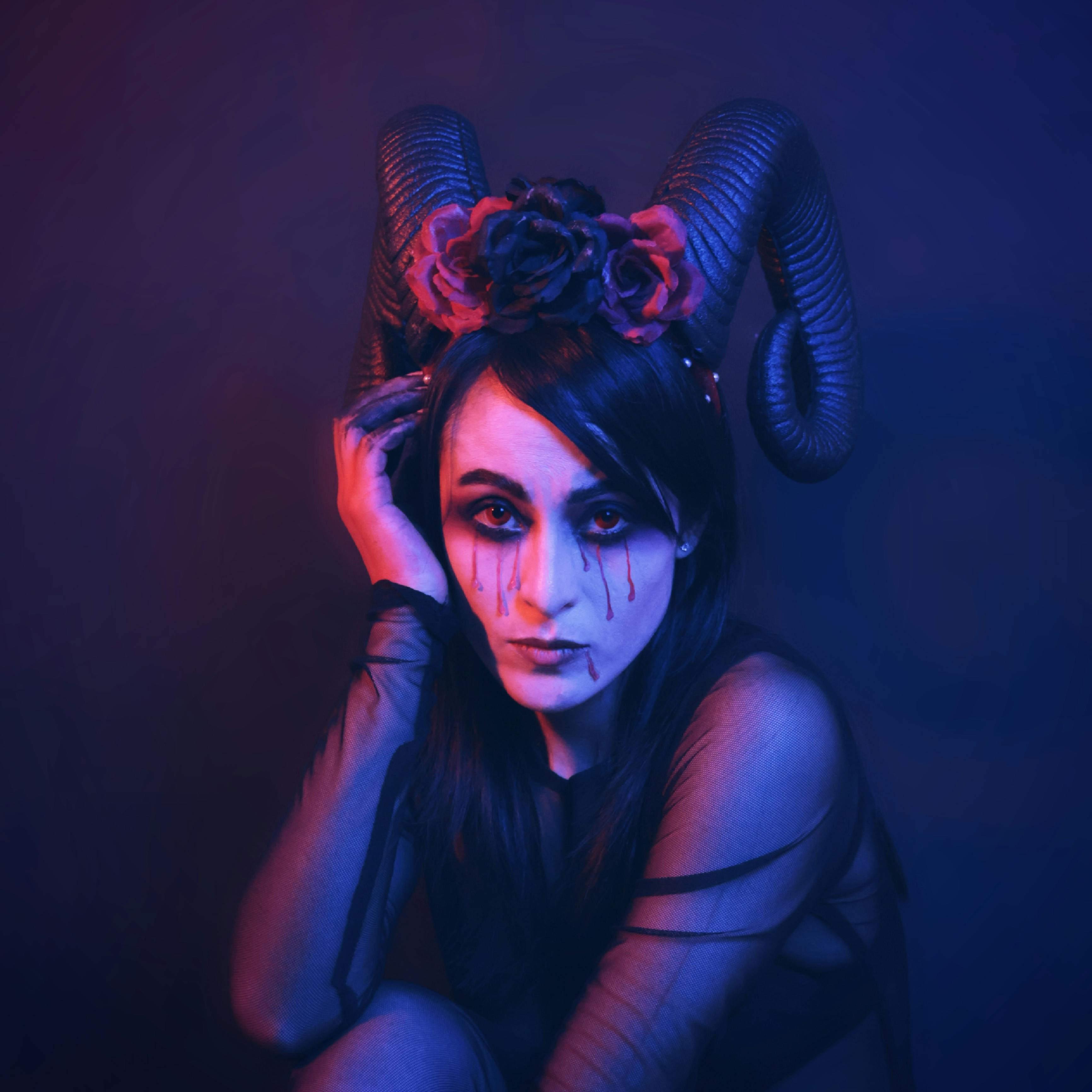 grátis Um retrato artístico e escuro de uma mulher com chifres e maquiagem gótica em iluminação vívida. Foto profissional