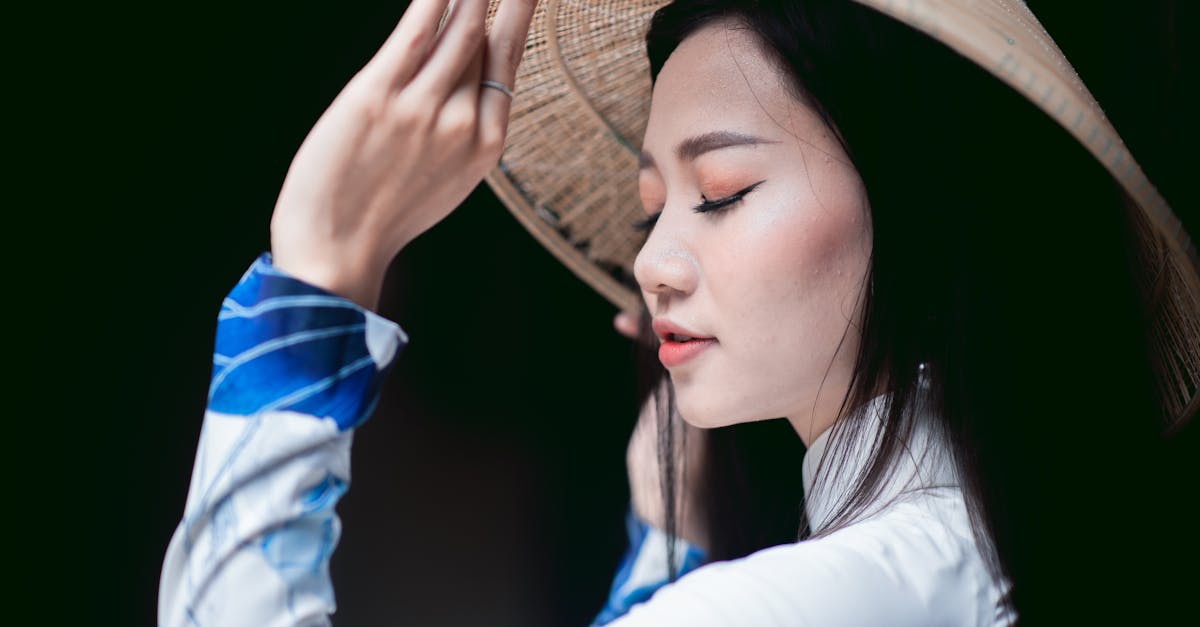 Side profile of a woman in a Vietnamese Ao Dai wearing a conical hat, deep in thought.