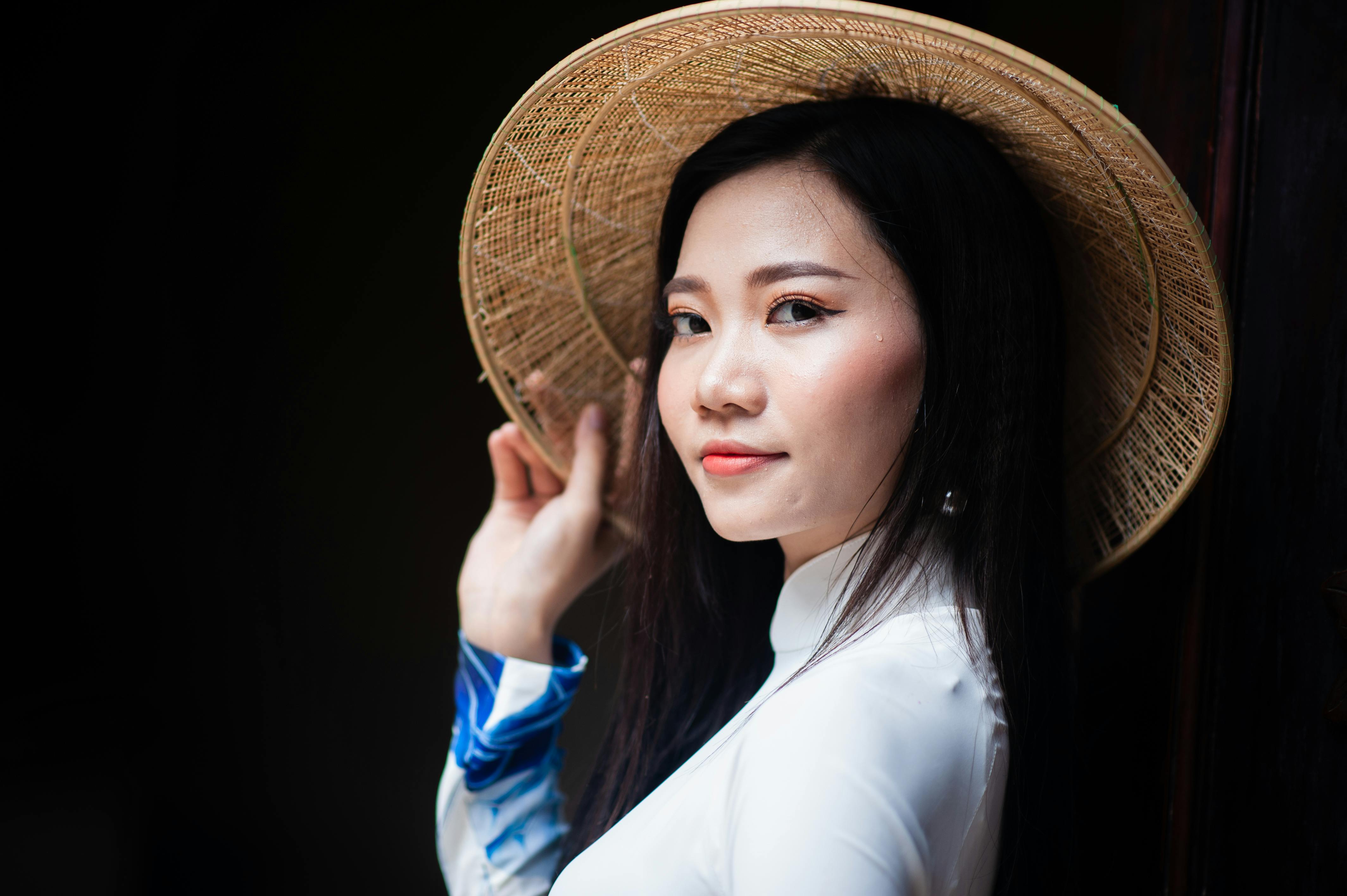 Portrait of a Vietnamese woman in Ao Dai and a straw hat, embracing cultural elegance.