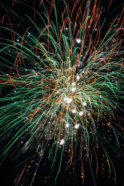 Free Colorful fireworks burst against a dark night sky, brightening the scene. Stock Photo