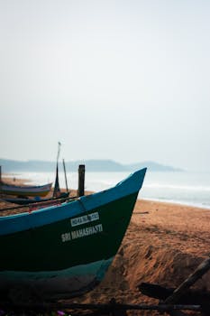 Fishing boats on the sandy shores of Gokarna, India, under clear skies.