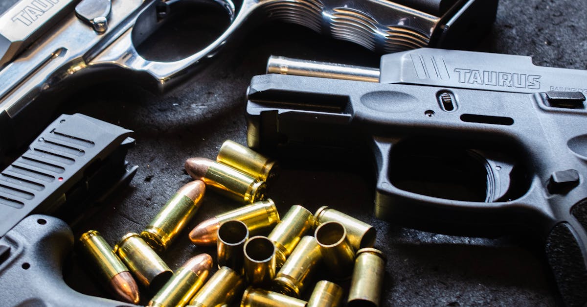 Photo by Matheus Lara Detailed shot of various handguns and bullets arranged on a textured dark surface, showcasing firearm elements.