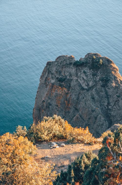 Free Dramatic view of a rugged cliff with autumn foliage by the sea, capturing natural beauty. Stock Photo