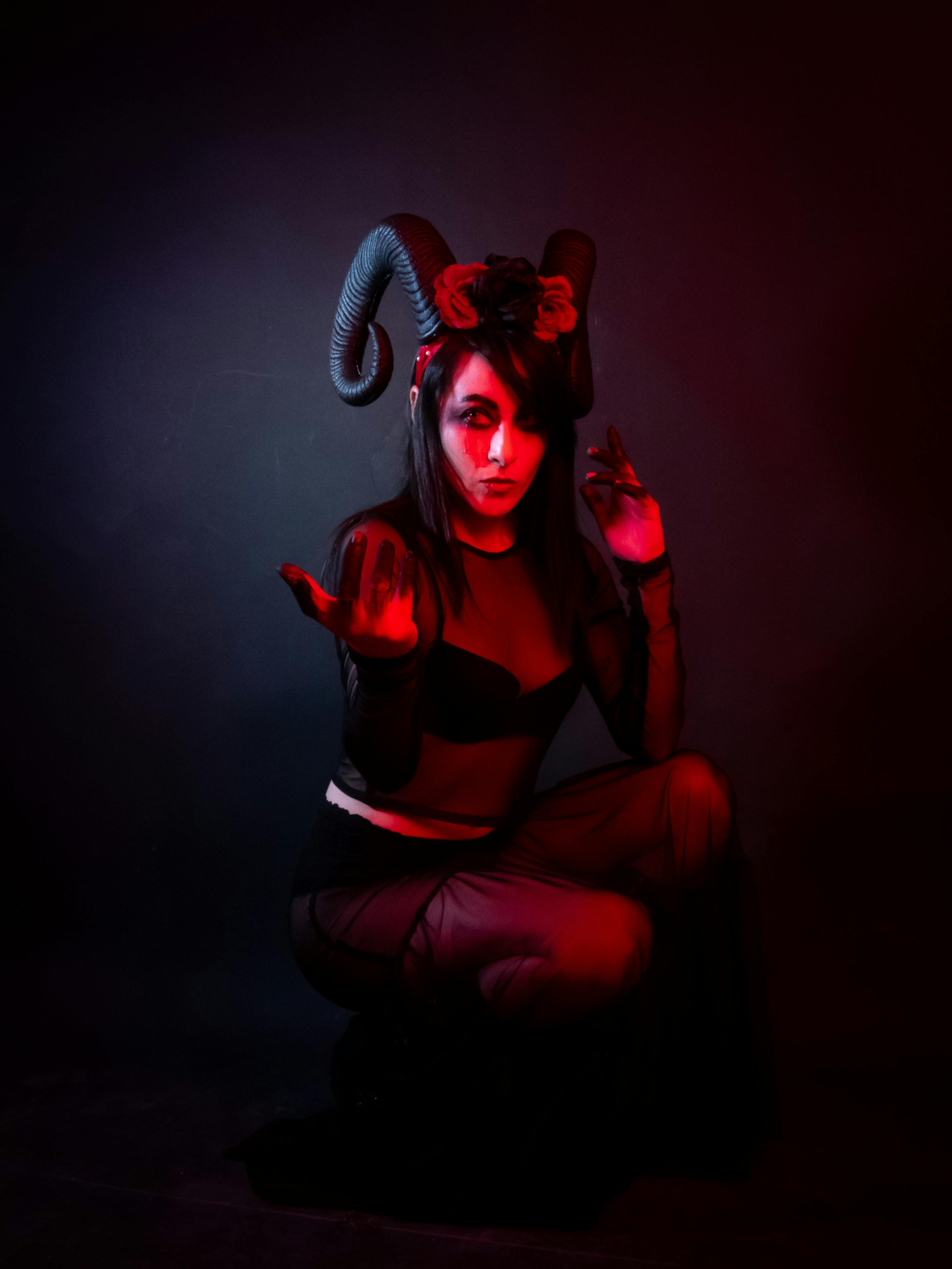 grátis Uma mulher com uma fantasia escura e dramática de demônio com chifres, transmitindo uma atmosfera de Halloween. Foto profissional