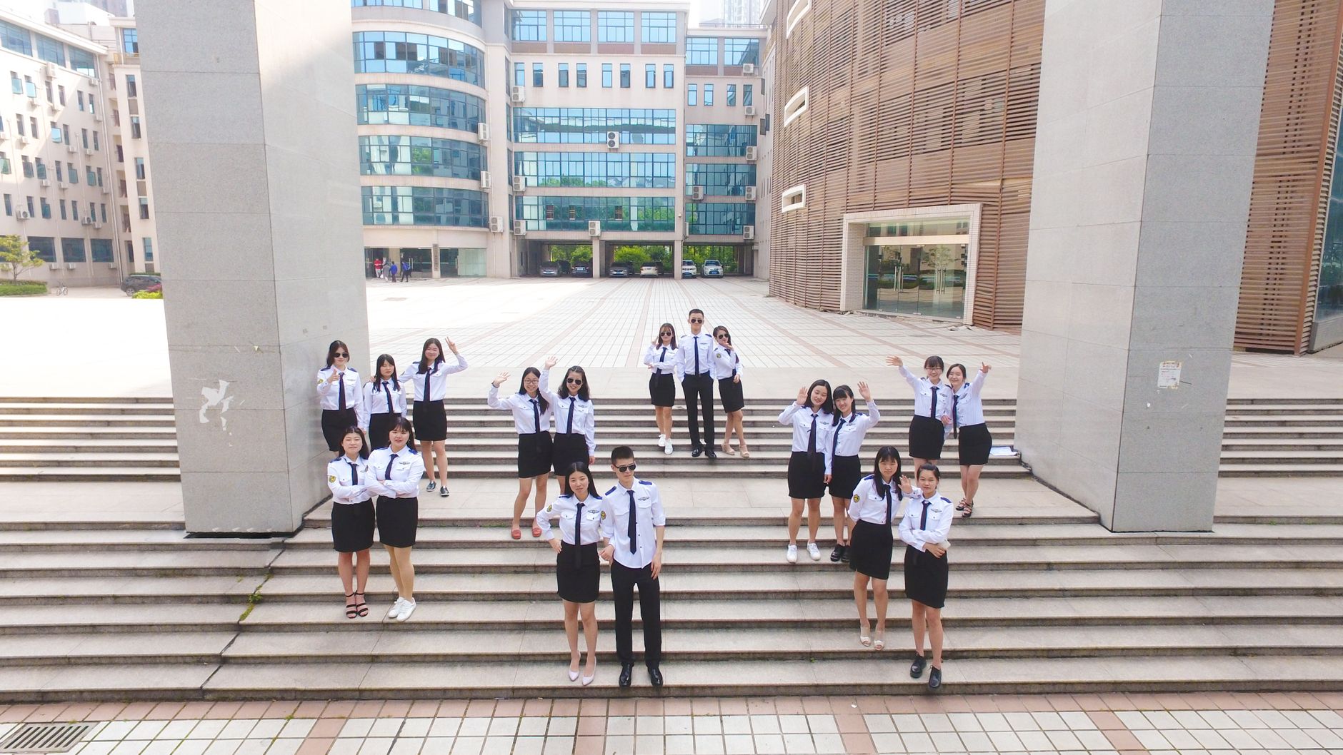 Group of high school students in uniform celebrating graduation on school steps outdoors.