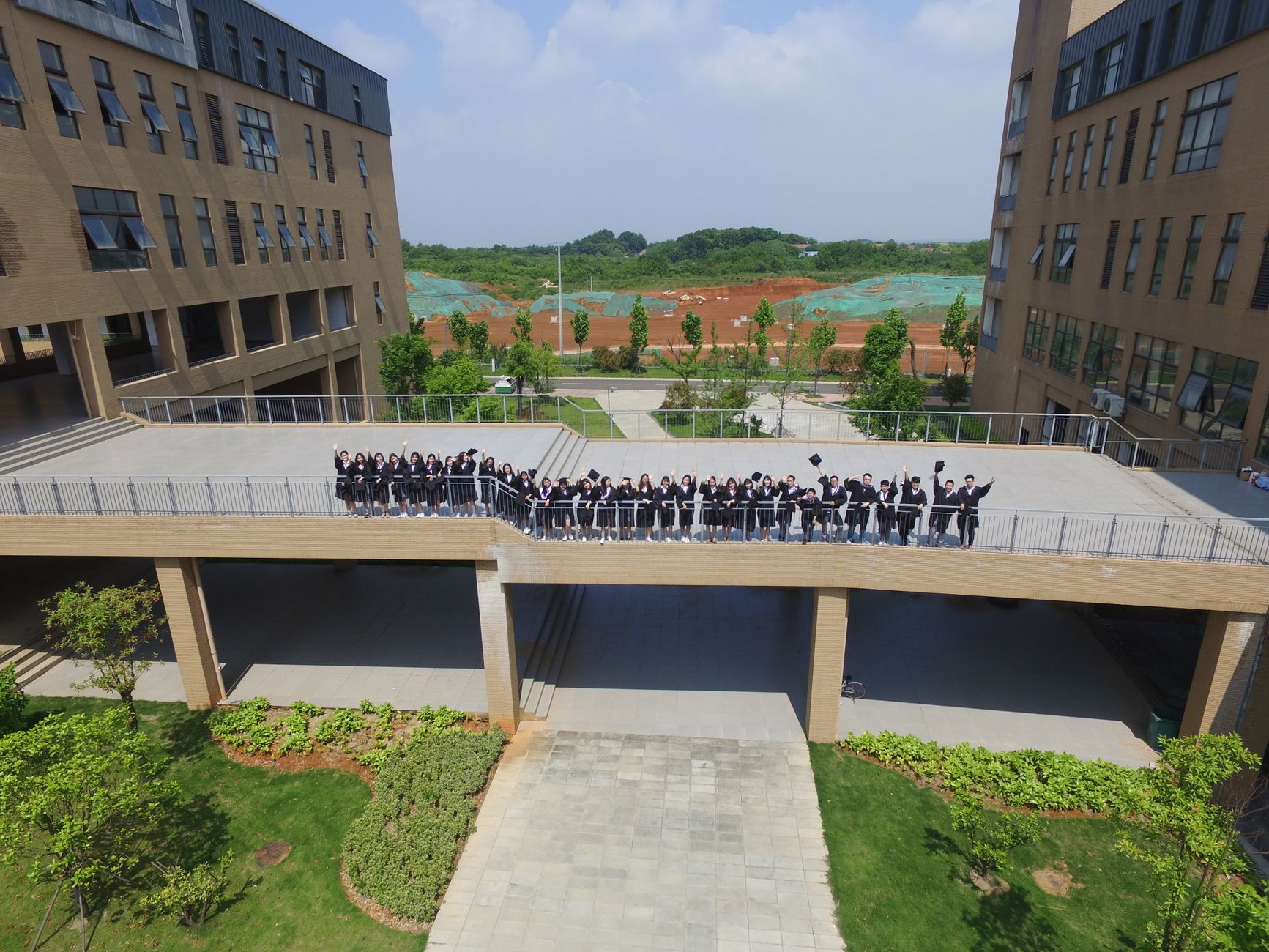Aerial shot of a group on a walkway between modern buildings, sunny day.