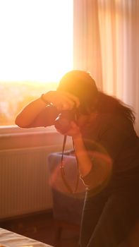 Photographer silhouetted by warm sunlight snapping a photo indoors.