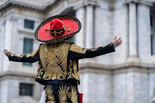 Free A person in traditional Mexican attire poses in front of a historic building in Mexico City. Stock Photo
