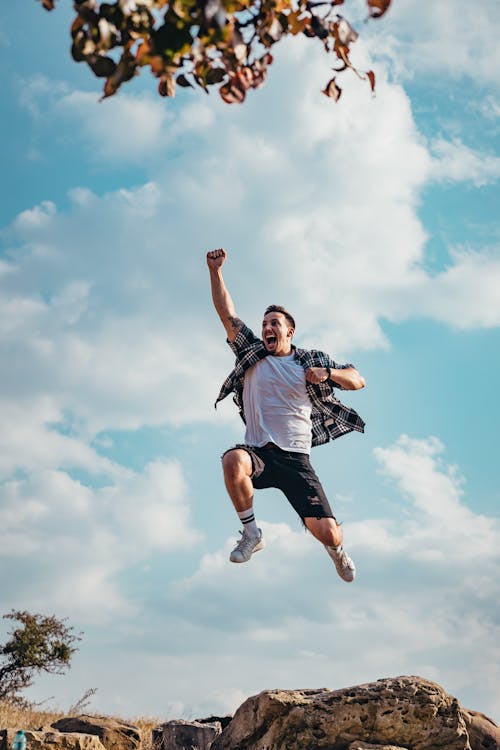 Free Man Jumping From A Rock Stock Photo