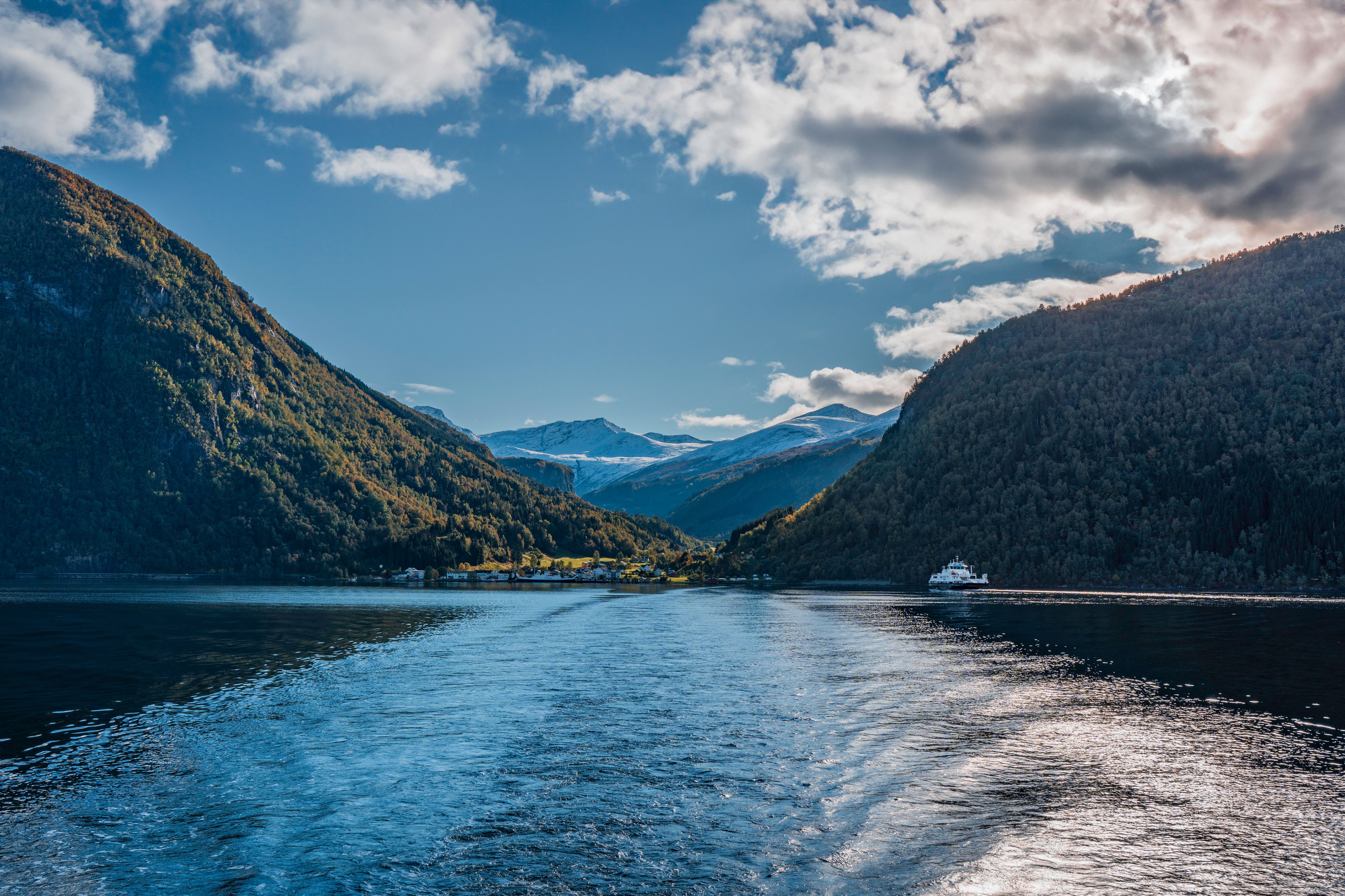 Norwegian fjord with dramatic cliffs, clear green water, and small boats in the distance