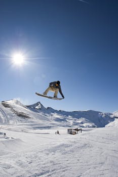 Snowboarder performing a high jump under clear skies in Livigno snowpark, Italy.
