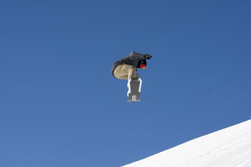 Free Snowboarder mid-air executing a trick against clear blue sky in Livigno, Italy. Stock Photo