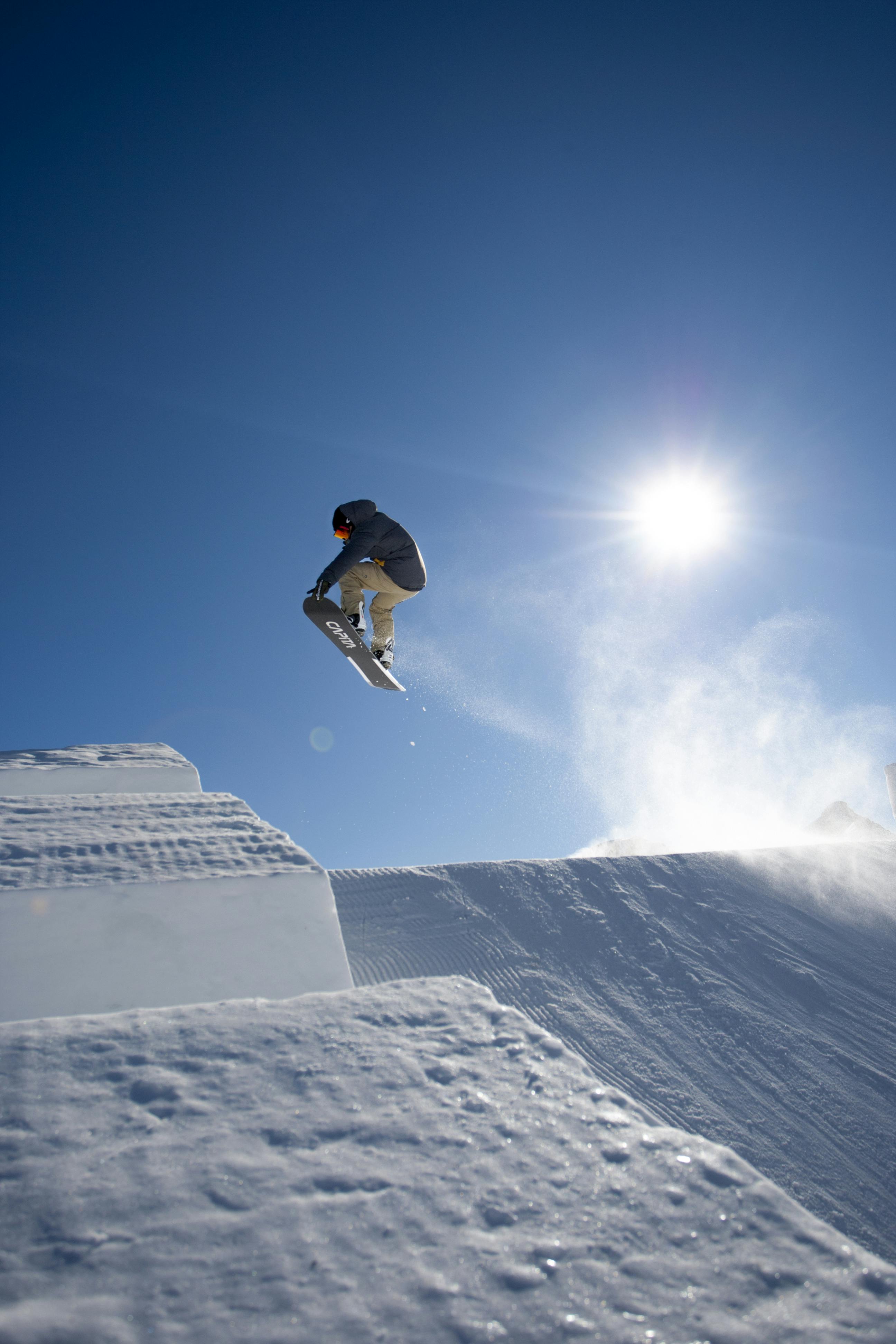 Prescription Goggle Inserts - A snowboarder performs a high jump on a bright sunny day at Livigno's snowpark.