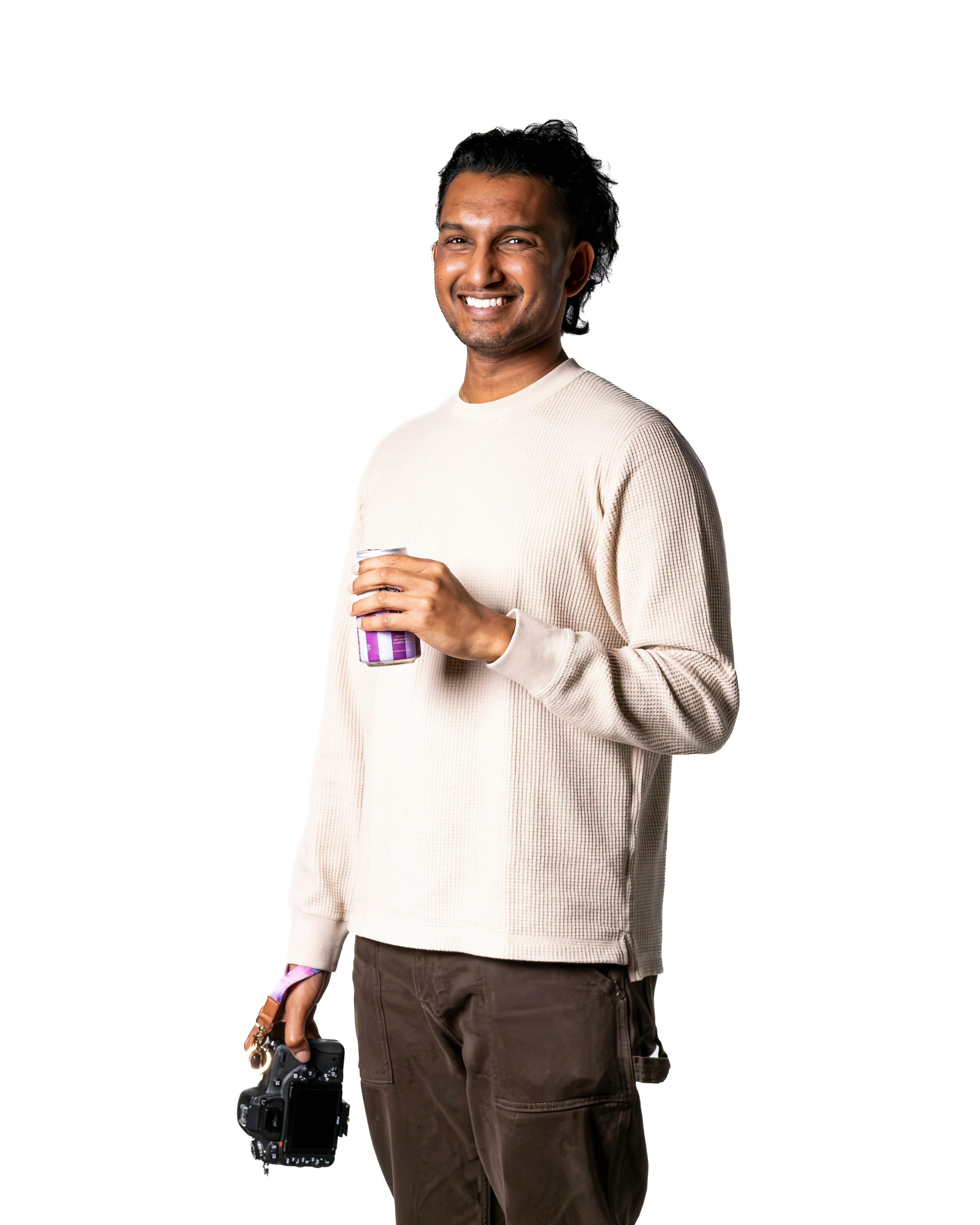 Ilmainen Iloinen mies pitelee kameraa ja kuppia valkoista taustaa vasten. Kuvapankkikuva