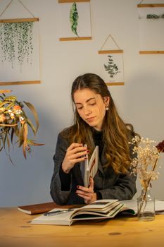 A young woman in a cozy office setting, reading a book with stylish decor. 29233079