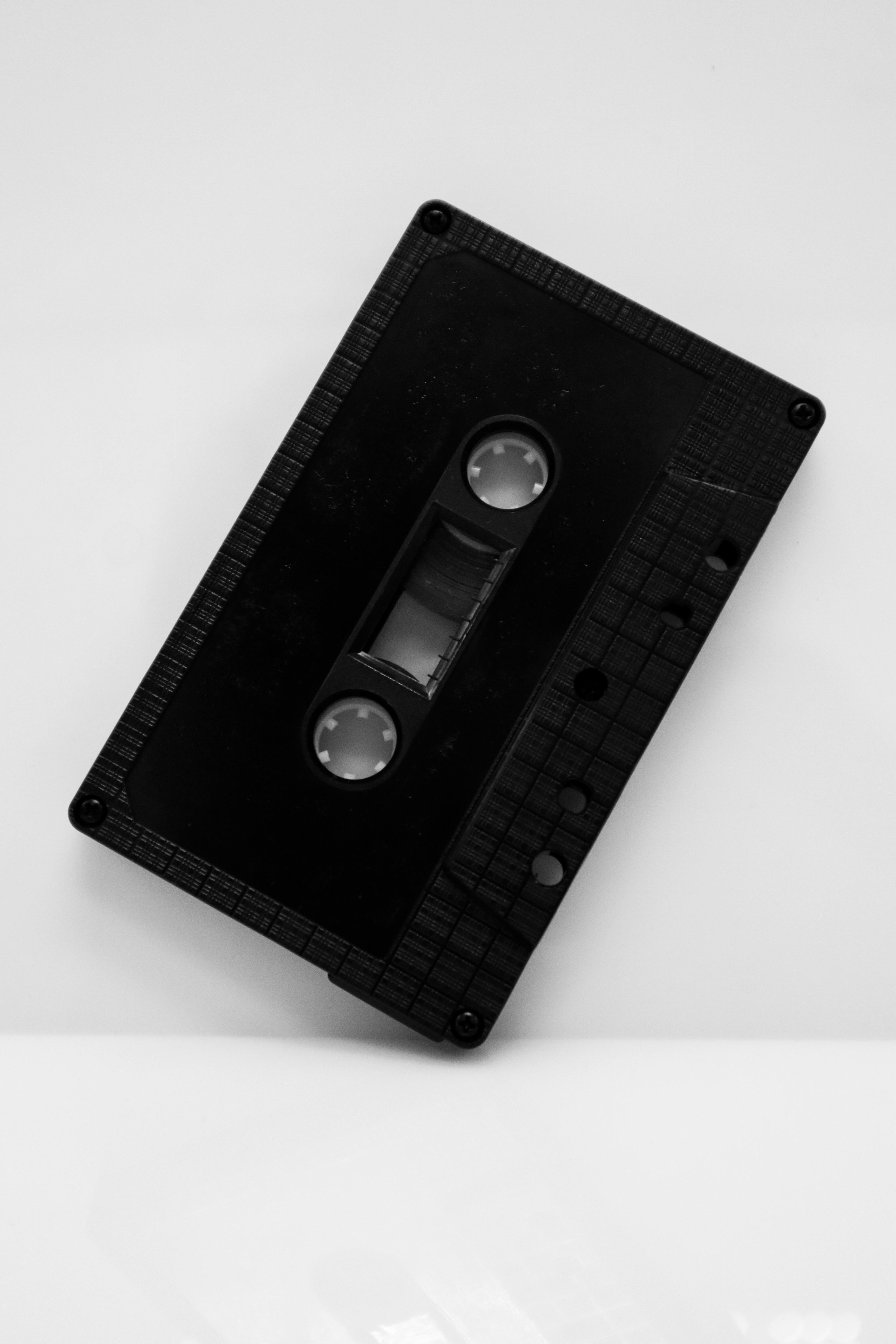 Gratis Una cinta de casete negra vintage colocada sobre un fondo blanco minimalista. Foto de stock