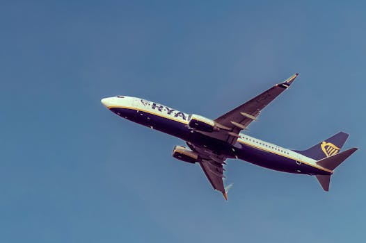 Commercial airplane flying over Sarajevo with a clear blue sky background.