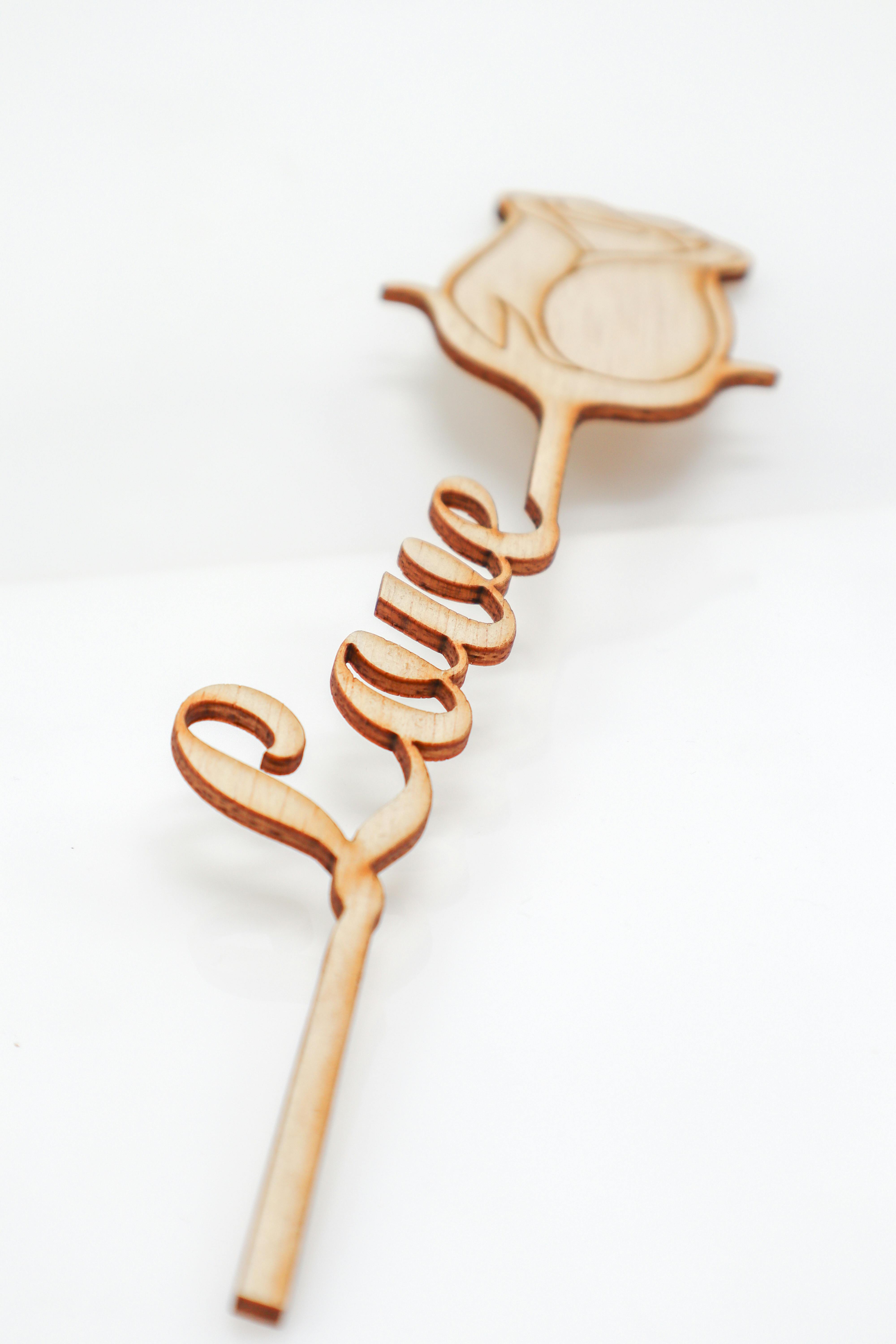 Elegant wooden stick with rose design spelling 'Love' in a script style.