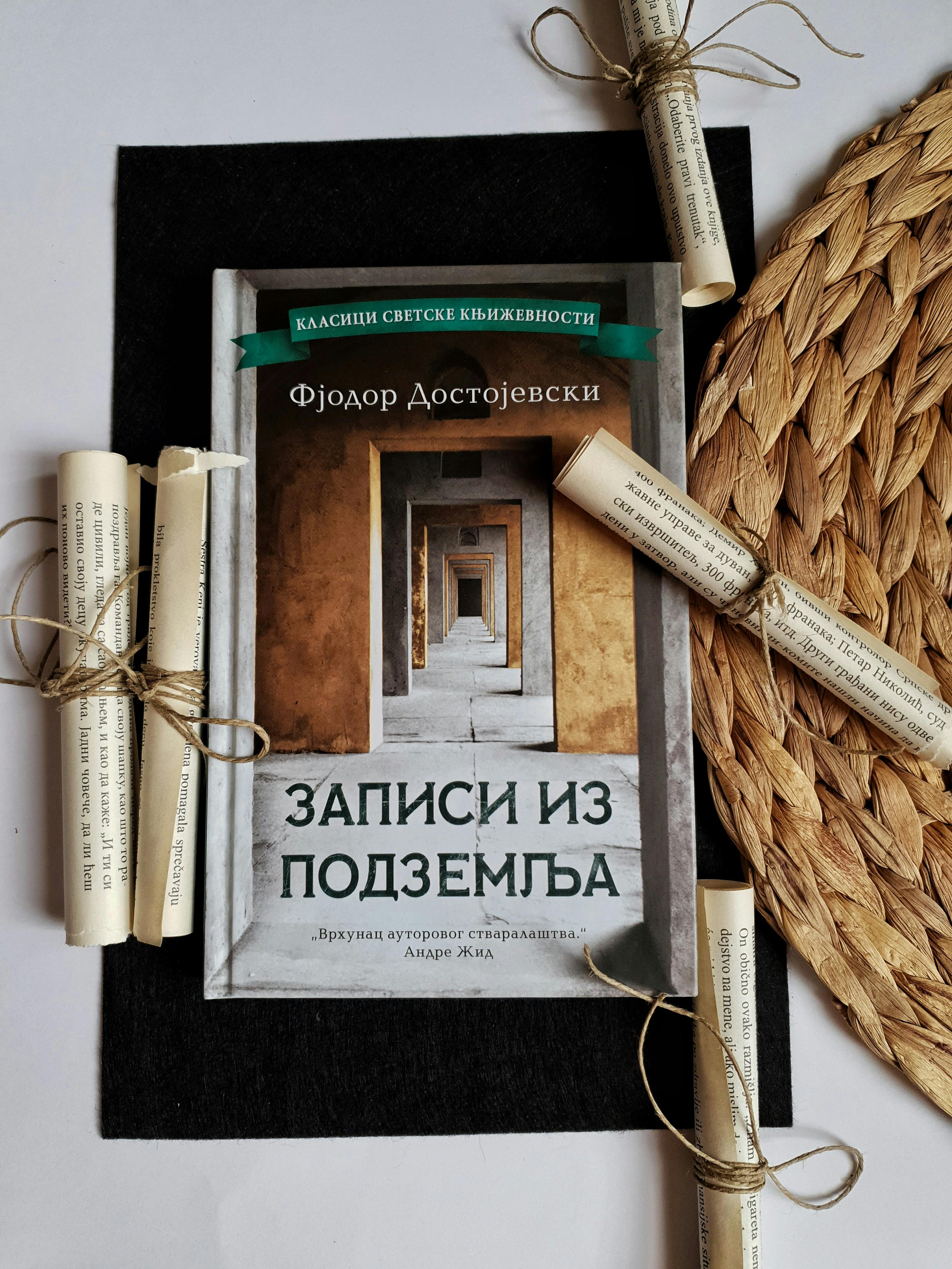 Dostoevsky's book styled with scrolls on a woven placemat and dark fabric.
