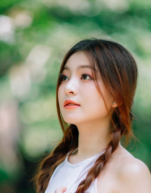Free Close-up portrait of a young woman with braided hair looking thoughtfully outdoors. Stock Photo