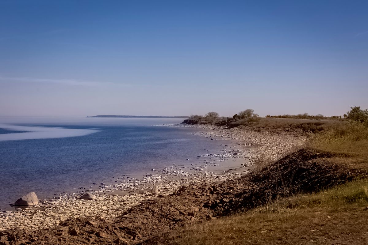A sandy beach stretching along the Swedish south coast, the sea calm and pale blue under a clear summer sky