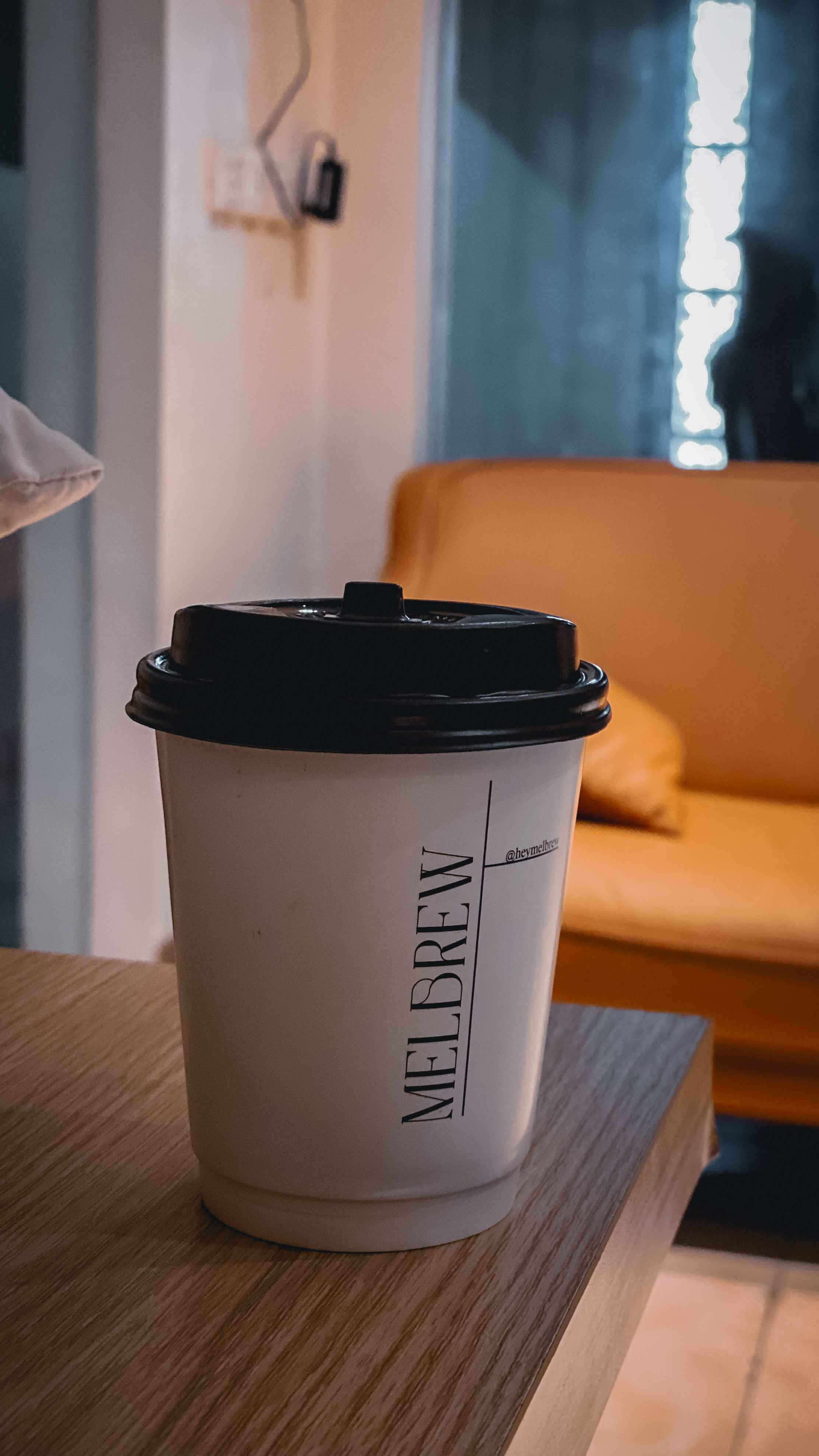 Fotomural Vaso de café desechable en una cafetería interior con asientos acogedores.