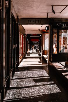 阳光明媚的城市走廊里，商店展示着阴影与步行的个人