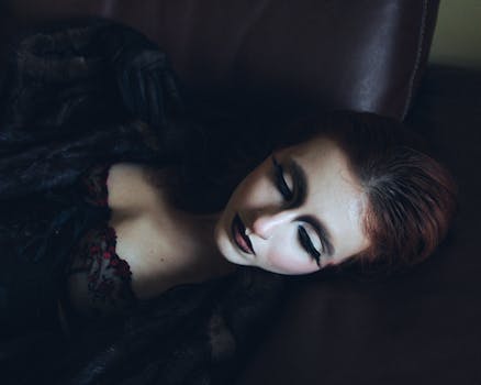 Elegant portrait of a woman with dramatic makeup and red hair, captured indoors.