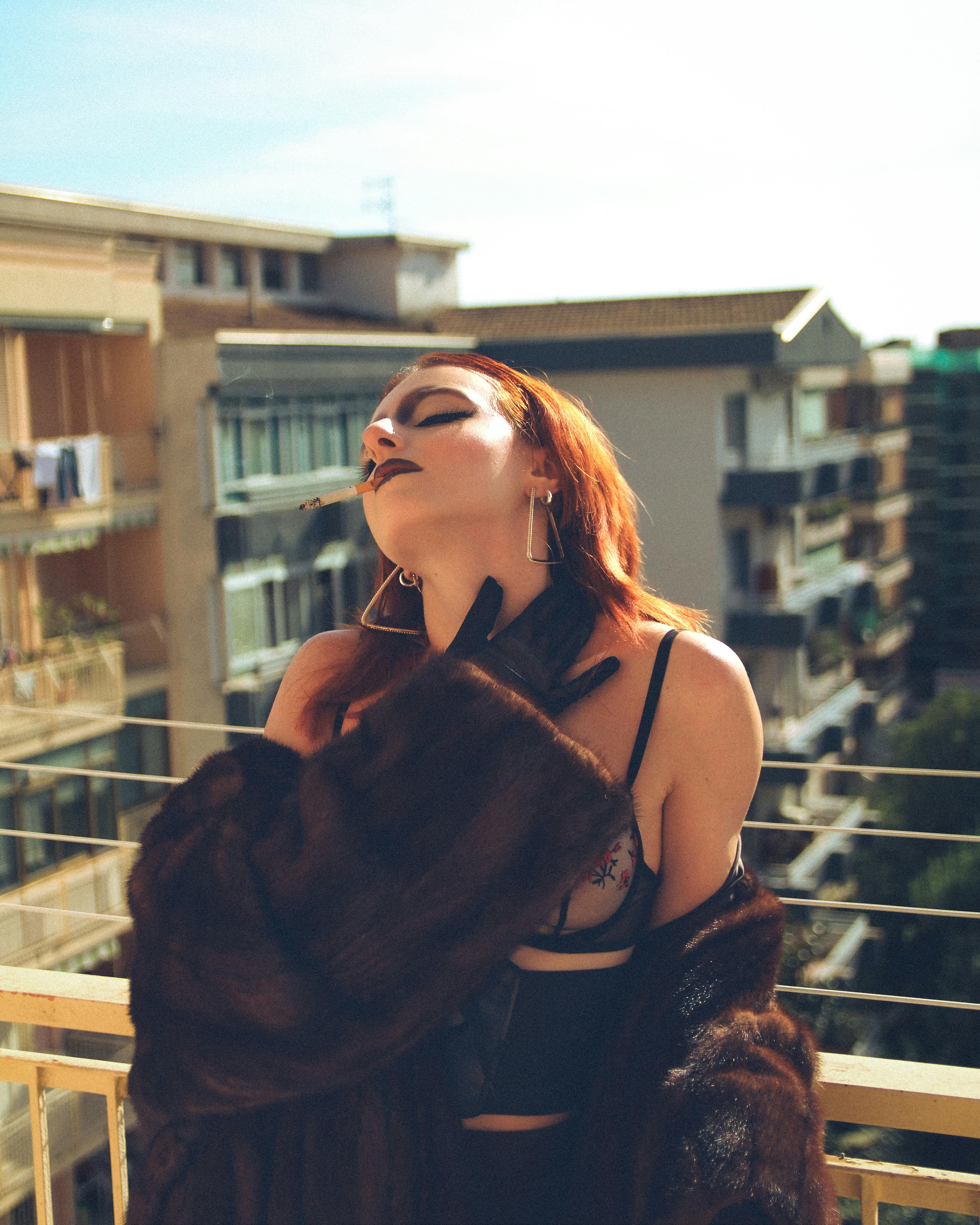 bezplatná Módní žena s červenými vlasy pózuje na balkoně v Caserta, Itálie, na sobě kožich. Základová fotografie