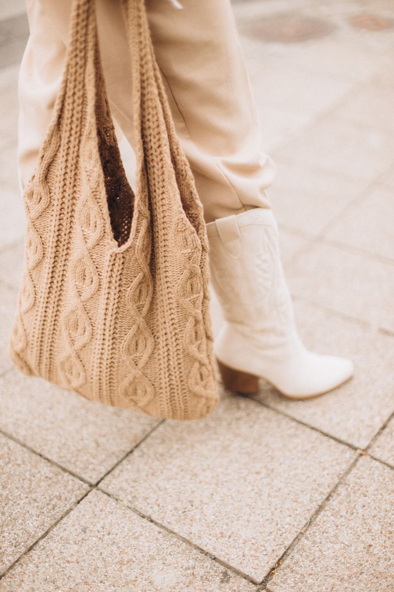Stylish beige cable-knit tote bag on autumn pavement
