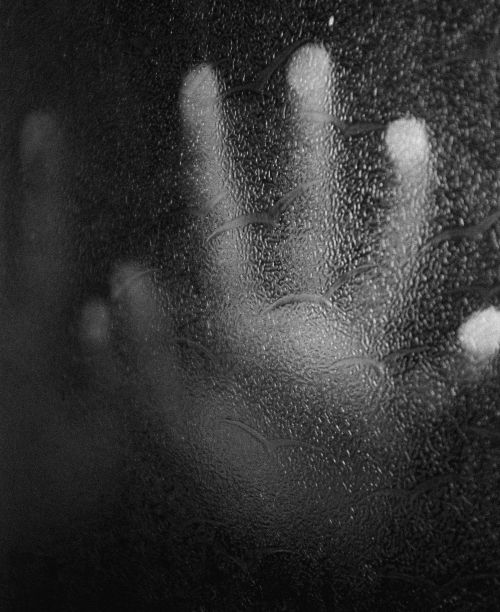 Free A black and white image of a hand pressing against a foggy glass, conveying mystery and suspense. Stock Photo