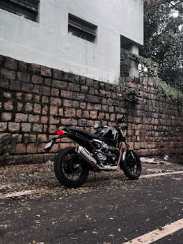 A sleek black motorcycle parked next to an old stone wall, capturing a blend of urban adventure and classic style in Bengaluru.