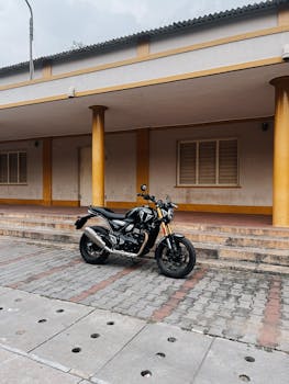 Classic black motorcycle parked against a yellow-columned building in an urban environment.