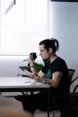 Tattooed man drinking coffee and working on tablet