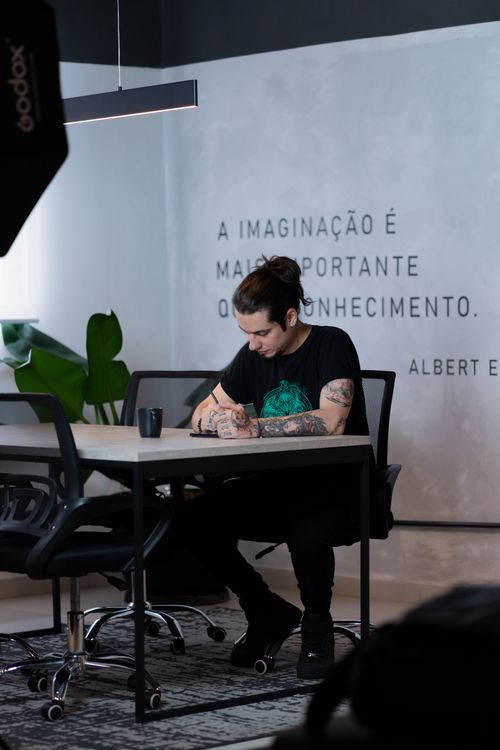 Free Young man focused on work in a stylish office with Albert Einstein quote on the wall. Stock Photo