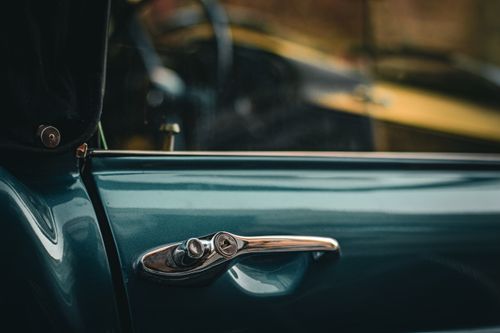 Free Detailed shot of a metallic blue vintage car door handle with subtle reflections. Stock Photo