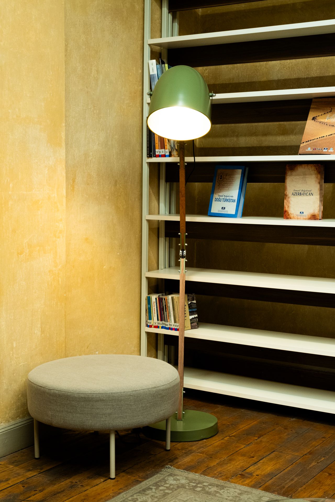 cozy-reading-corner-living-room Cozy reading corner with bookshelf, green lamp and round ottoman