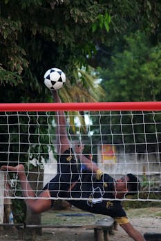 Athletic futevôlei player performing a high kick on Ilhéus beach, Brazil.