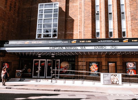 Exterior view of a brick theater showcasing current movie advertisements in an urban setting.