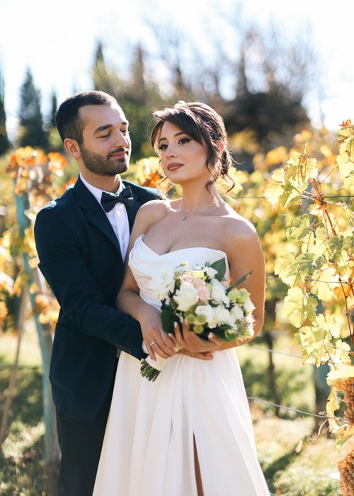 Free A romantic newlywed couple poses in a vineyard setting, capturing elegant wedding moments. Stock Photo
