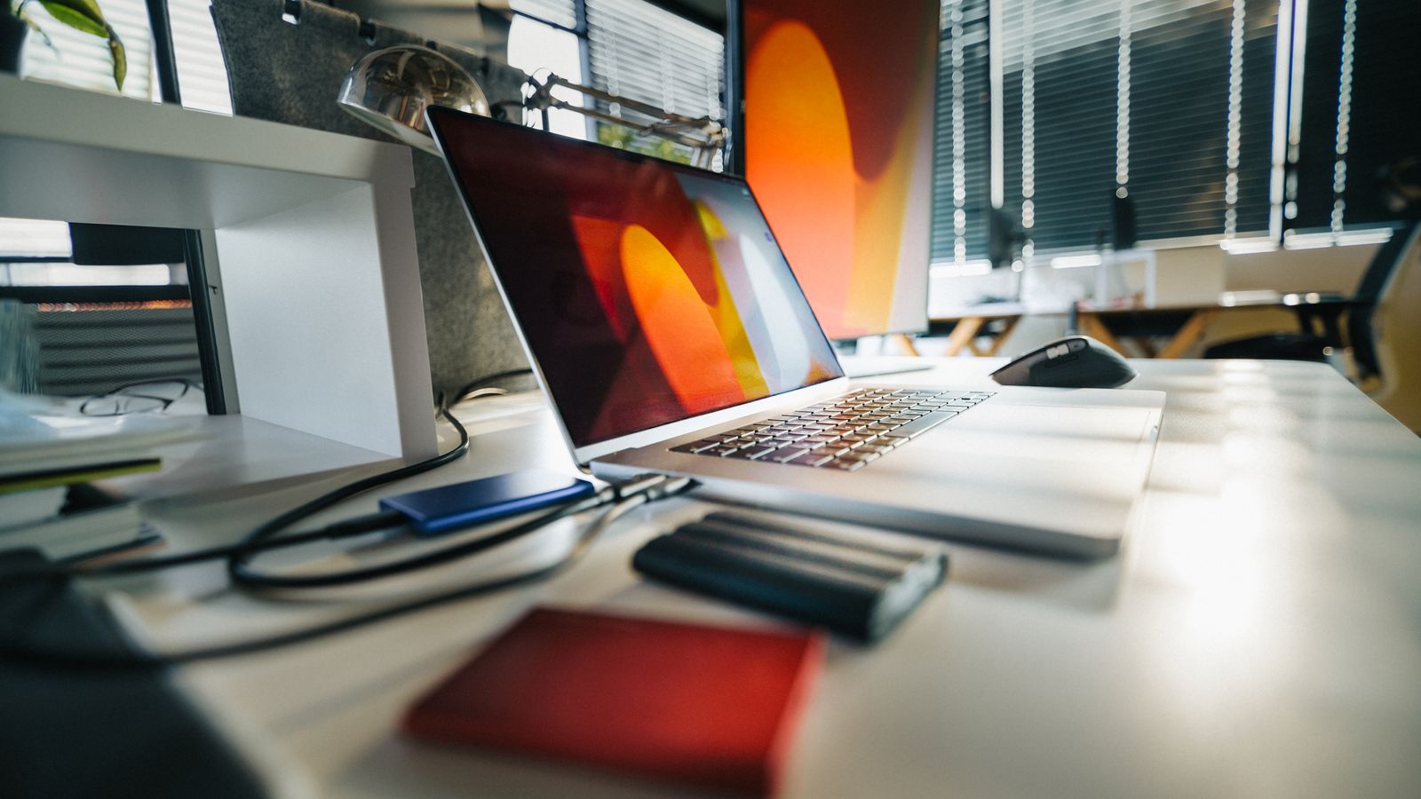 A desk with a laptop and external drives in a modern workspace