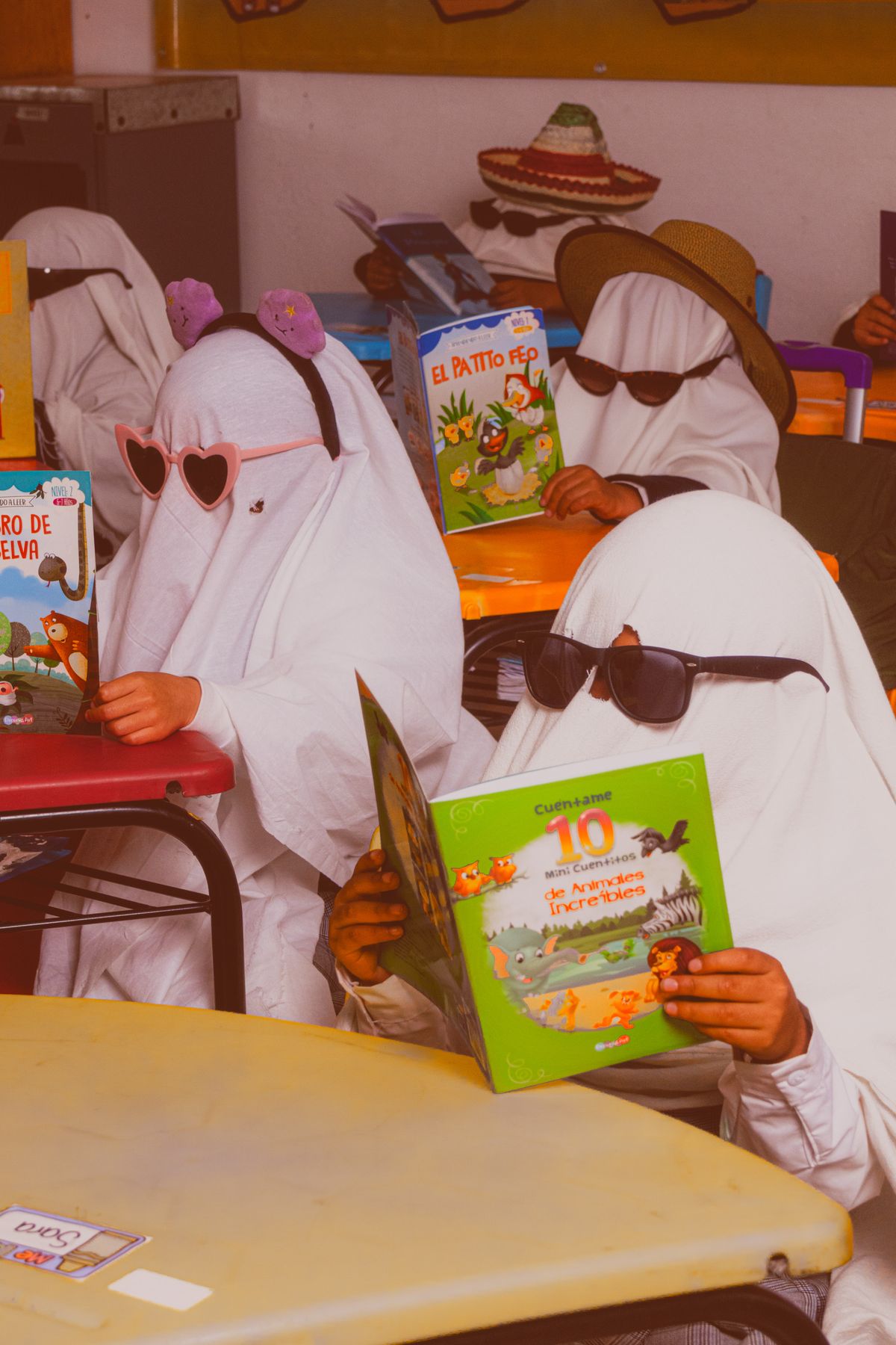 Kids in sheet ghost costumes reading a picture book together