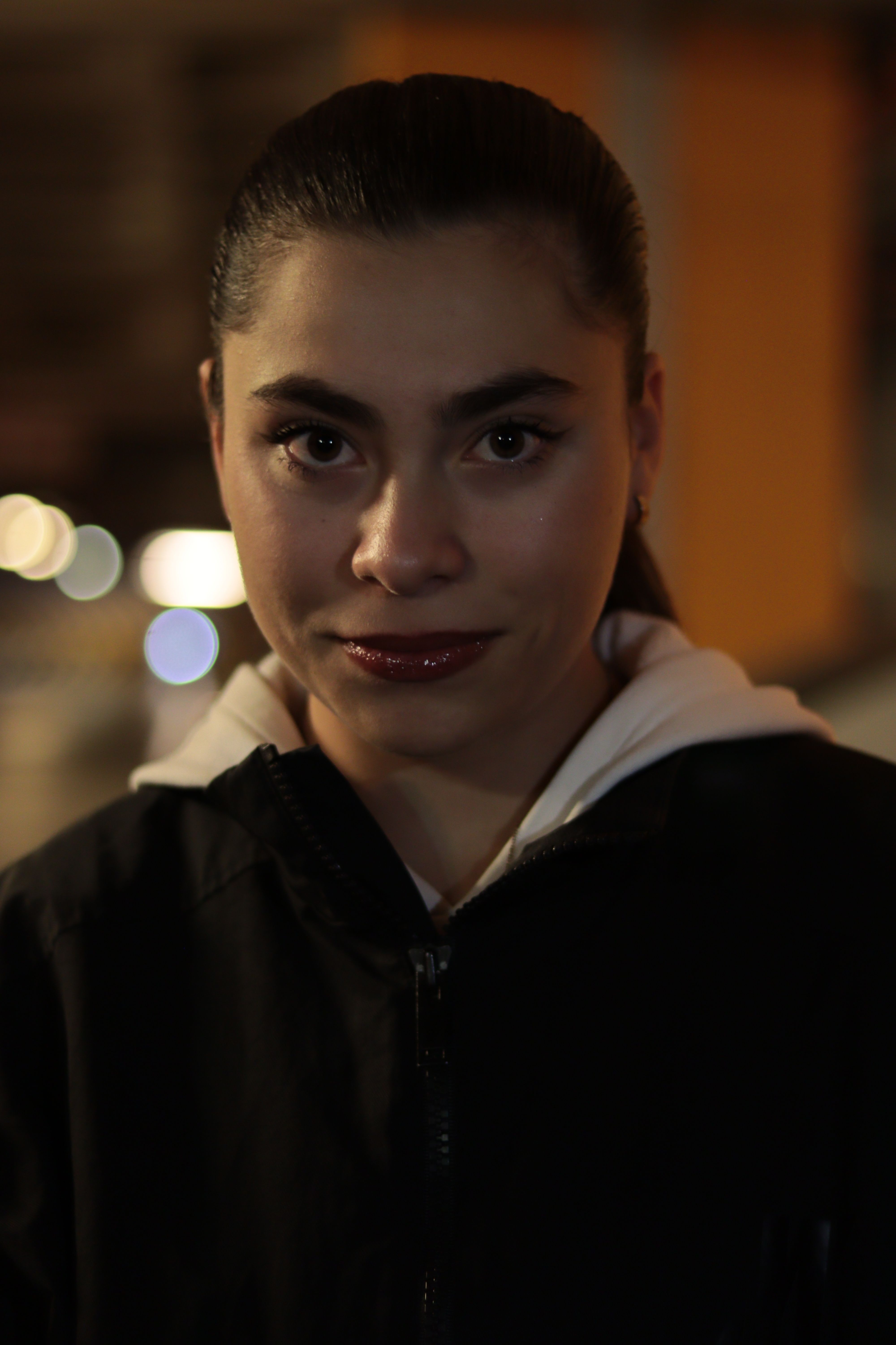 Moody portrait of a woman against a blurred urban night background.