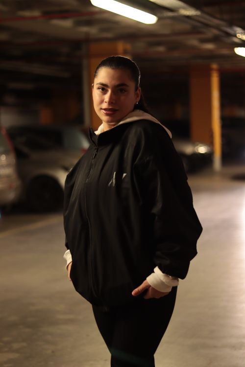 Free A young woman in a black jacket stands in an underground parking garage. Stock Photo