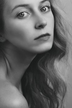A captivating grayscale portrait capturing the intense gaze of a young woman with flowing hair.
