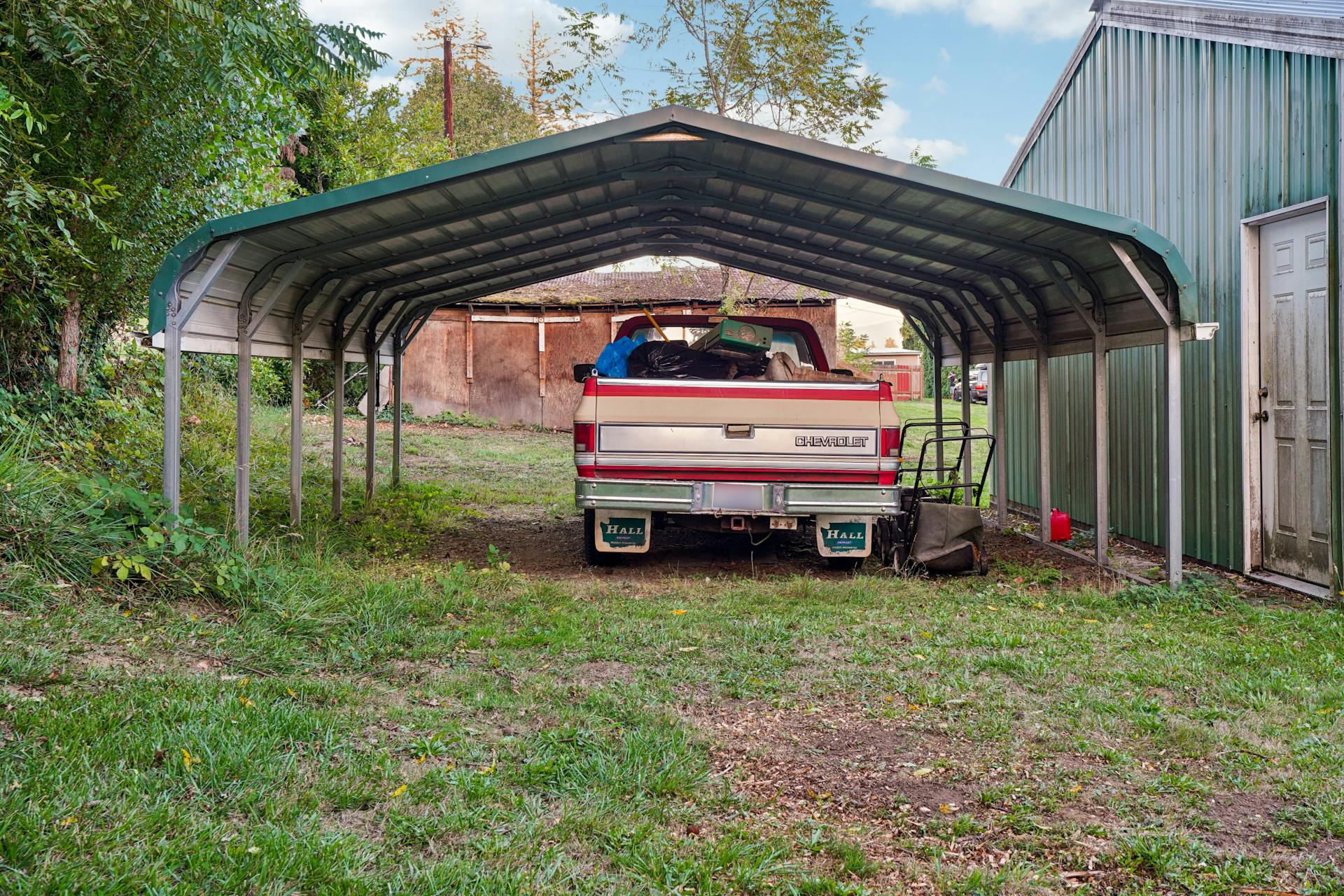 A Chevrolet truck loaded with items parked under a metal carport.